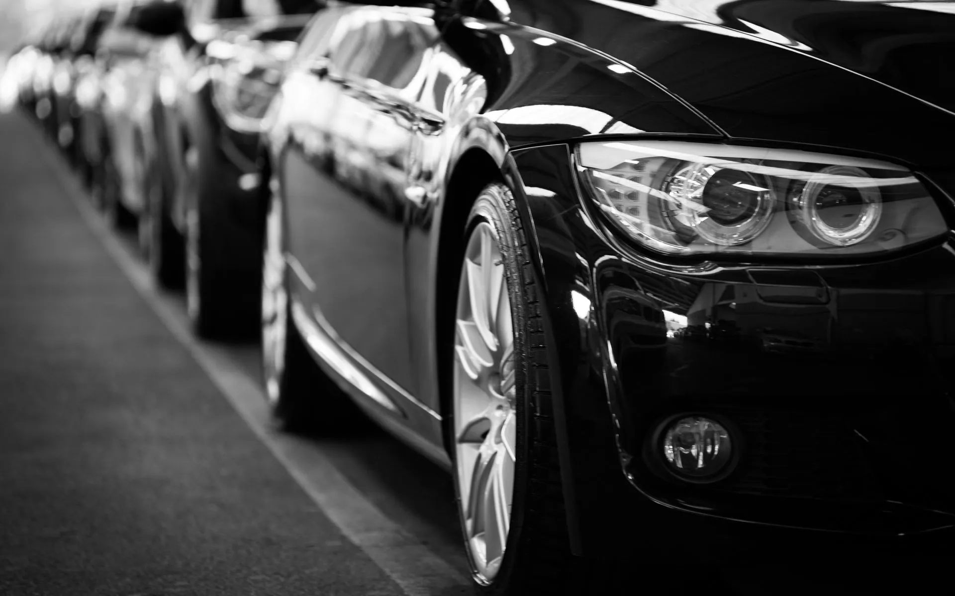 Black cars parked in a row with shiny rims.